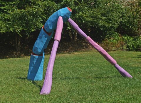 Blue and purple angled tripod sculpture on grass, with jointed leg-like supports