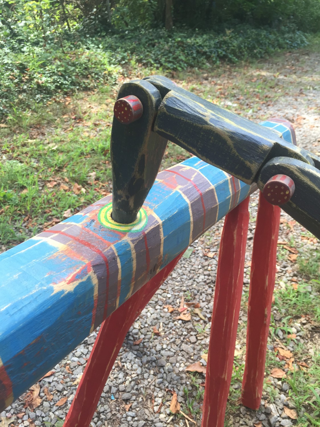 Close-up of a striped wood sculptures joint, showing a black articulated arm attached to a painted log